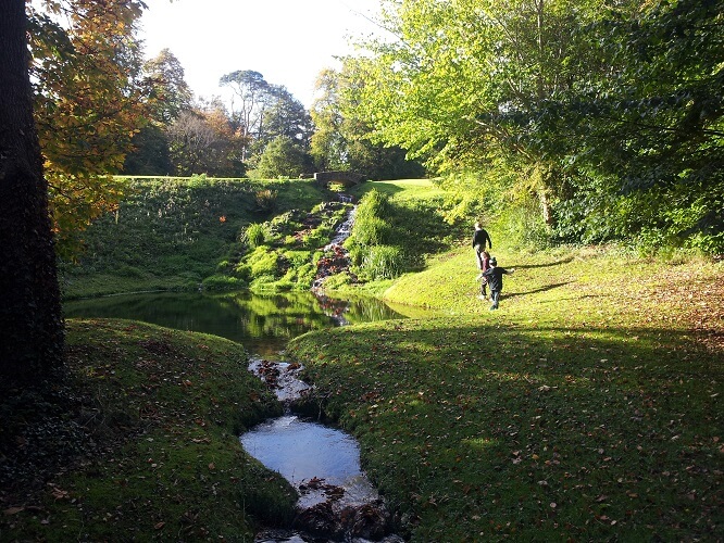 Kids playing by a pond with a stone bridge in the background
